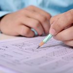 person writing on answer sheet