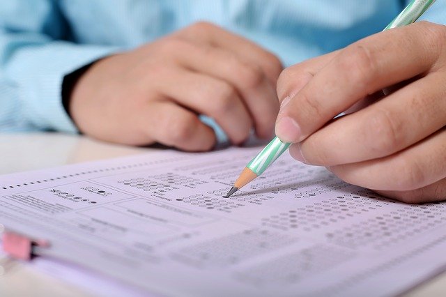 person writing on answer sheet