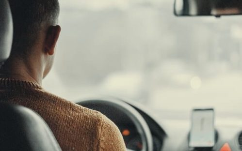 driver wearing brown sweater facing the driving wheel