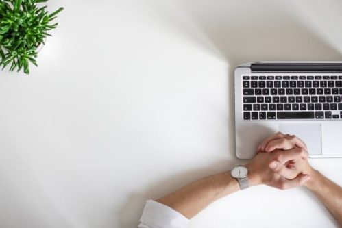 fingers intertwined in front of a laptop