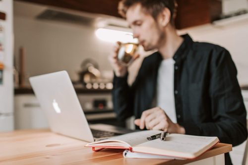 man drinking in front of laptop