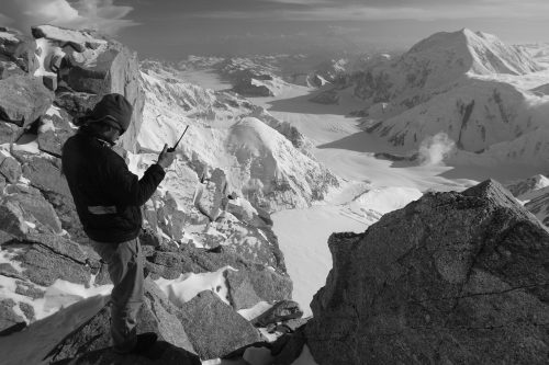 man standing on mountain with two-way radio