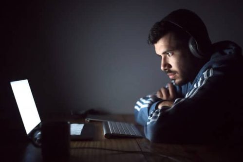 man wearing headphones staring at a laptop screen