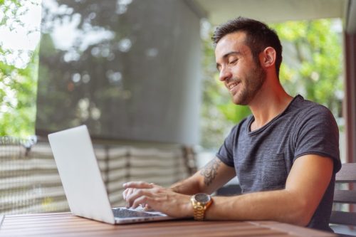 man with gray shirt typing on laptop
