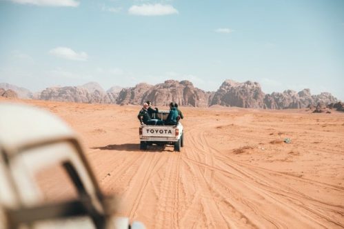people riding the back of a truck on the desert